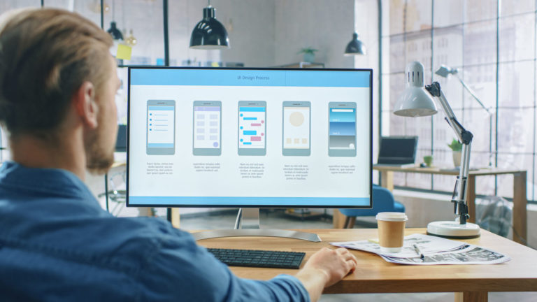 Young Professional Works on a Personal Computer at His Desk in t
